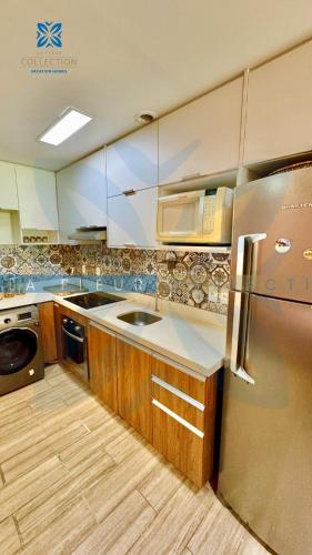 a kitchen with a stainless steel refrigerator and wooden cabinets at La Fleur Collection Vacation Homes - Residence & Resort in Porto De Galinhas
