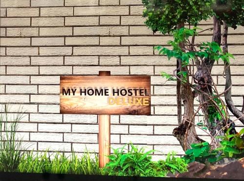 a wooden sign in front of a brick wall at My Home Hostel Deluxe Lüdinghausen in Lüdinghausen