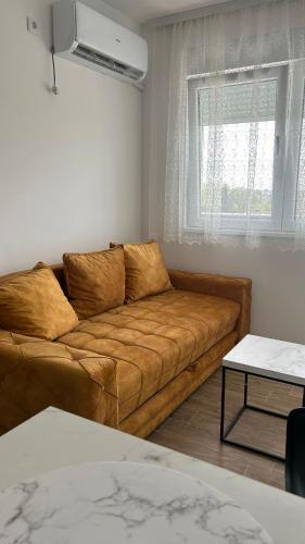 sala de estar con sofá marrón y ventana en Stan na dan Indjija, en Inđija