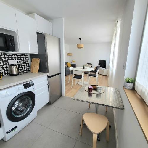 - une cuisine et un salon avec un lave-linge et une table dans l'établissement Le Gouedic - 2 chambres - 3 lits - 60m2, à Saint-Brieuc