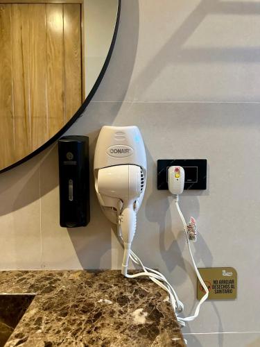 a hair dryer on a wall next to a mirror at Hotel y Cabañas Covemar in Coveñas