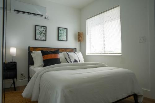 a bedroom with a bed with white sheets and a window at The Jaxon in West Palm Beach