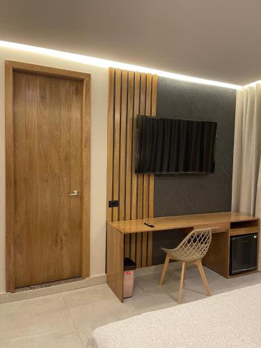 a room with a desk and a television on a wall at Hotel y Cabañas Covemar in Coveñas