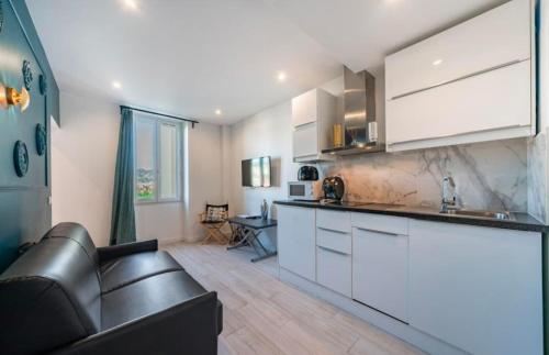 une cuisine avec des placards blancs et un canapé en cuir noir dans l'établissement Close to train station and palace, quiet, à Cannes