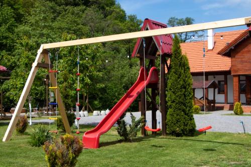 a playground with a red slide in a yard at Patakmenti Panzió Spa in Corund