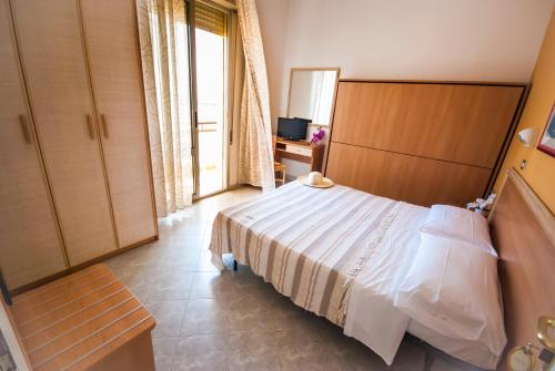 Schlafzimmer mit einem weißen Bett und einem TV in der Unterkunft Hotel Lungomare in Bellaria-Igea Marina