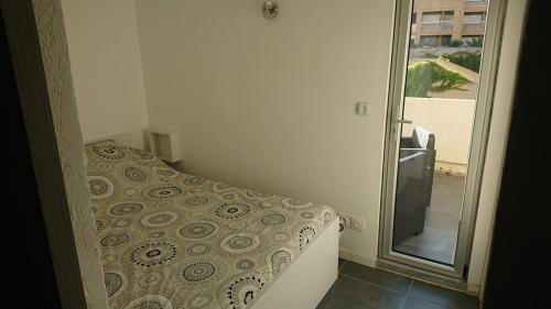 - une petite chambre avec un lit et une porte coulissante en verre dans l'établissement Centre Port Cap d 'agde, au Cap d'Agde