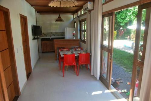 a kitchen with a table and red chairs in it at Flete Pé na Areia - Barra Grande in Marau