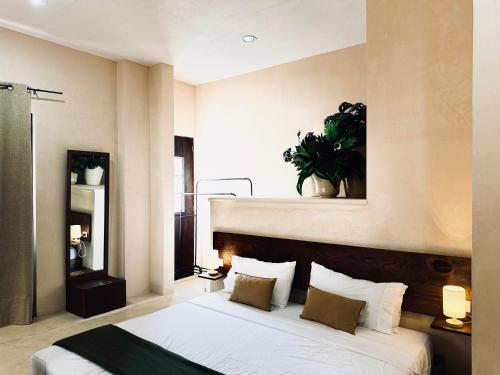 a bedroom with a bed with a plant on the wall at Hotel Casa Nudo, Mérida in Mérida