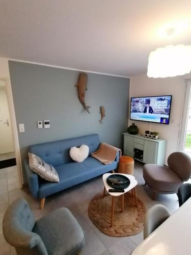 un salon avec un canapé bleu et des chaises dans l'établissement Nice house - Sainte Cécile beach 2 min away, à Camiers