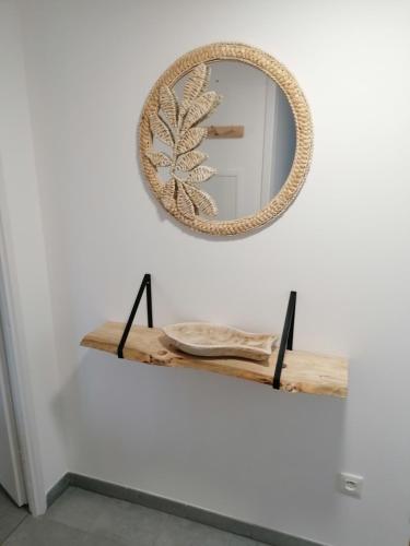 un miroir sur un mur avec une étagère en bois dans l'établissement Nice house - Sainte Cécile beach 2 min away, à Camiers