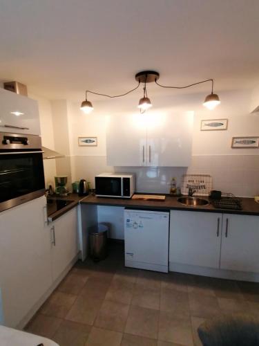 une cuisine avec des armoires blanches et un micro-ondes dans l'établissement Nice house - Sainte Cécile beach 2 min away, à Camiers