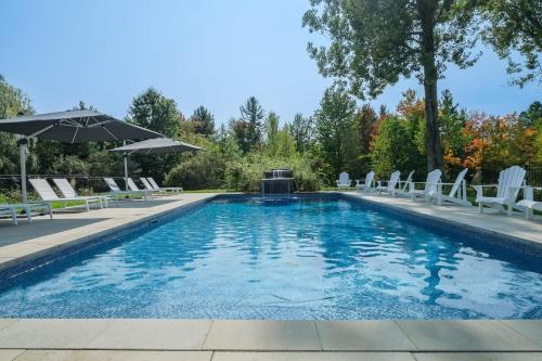 a swimming pool with chairs and an umbrella at Bromont Lodge 837 shefford suite 200 in Bromont