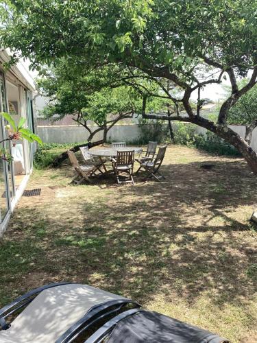 une arrière-cour avec une table et des chaises sous un arbre dans l'établissement Maison sainte marie de ré, à Sainte-Marie de Ré