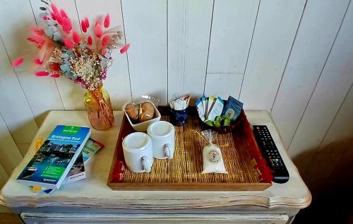 a table with a tray with cups and a remote control at Chambre paisible avec jardin à la campagne en Finistère sud in Scaër