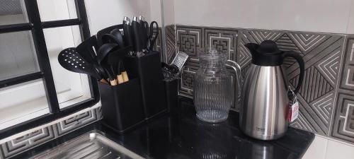 a black counter top with utensils in a holder at Serene BnB - Apt 06 Makongo after Mlimani City in Dar es Salaam