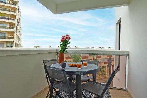 d'une petite table et de chaises sur un balcon avec fenêtre. dans l'établissement Appartement Melgueil - Welkeys, à La Grande Motte