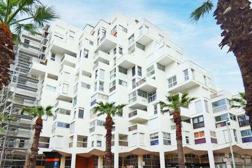 un bâtiment avec des palmiers devant dans l'établissement Appartement Melgueil - Welkeys, à La Grande Motte