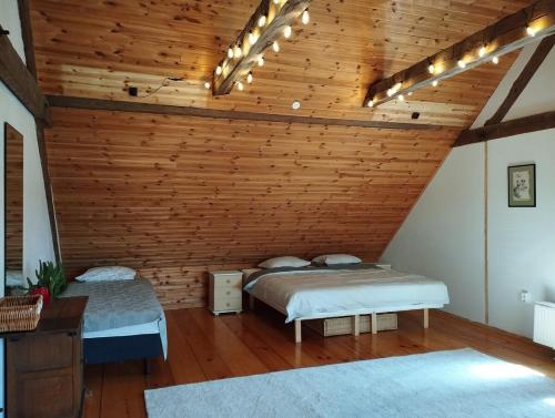 two beds in a room with a wooden ceiling at Hubane korter Mooste mõisa ajaloolises veskis - Cozy apartment in Mooste in Mooste
