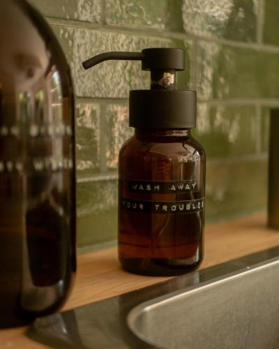a bottle of soap sitting on a counter next to a sink at Fleur de Marguerite in Sint-Martens-Latem