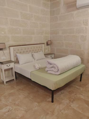a bed with white sheets and pillows on it at St Joseph Building Central Rooms in Hamrun