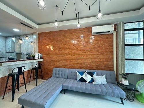 a living room with a couch and a brick wall at City House Don Mueang Airport Bangkok in Don Muang Airport