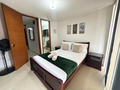 a bedroom with a large bed with white sheets and green blanket at Beautiful house with a pool in Pereira in Pereira