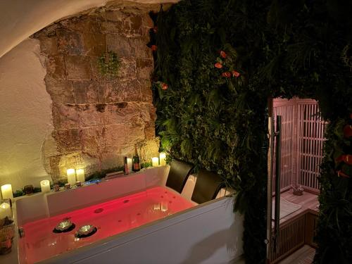 une baignoire rouge avec des bougies dans un mur de pierre dans l'établissement Moment Aixois, à Aix-en-Provence