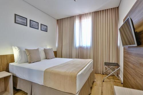 a hotel room with a large bed and a window at Nobile Inn London Anápolis in Anápolis