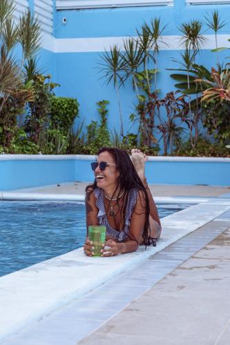 a woman sitting next to a pool talking on a cell phone at Rainbow Suites in Cozumel