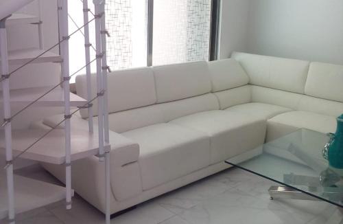 a white couch in a living room with a glass table at Palmarena Rooms & Residences - Long Stay Comfort with Parking, Sauna, Gym & Pool - Steps from 5th Avenue in Playa del Carmen