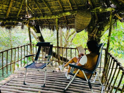 una persona seduta su una sedia che legge un libro di Drey at Druv Dakshin Farm Resort a Padinjarathara