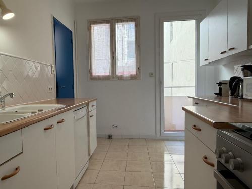une cuisine avec des armoires blanches et un évier dans l'établissement Appartement Mourillon vue mer, à Toulon