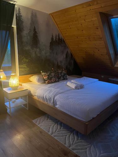 a bedroom with a large bed with a painting on the wall at CasaSol Domek w Beskidach in Sól