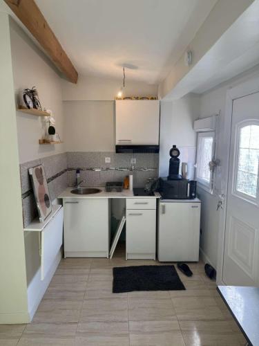 une cuisine avec des armoires blanches et un comptoir dans l'établissement studio calme, à Les Pavillons-sous-Bois