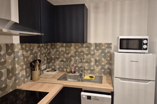 une petite cuisine avec un évier et un micro-ondes dans l'établissement Apartment with terrace in the city center, à Saint-Tropez