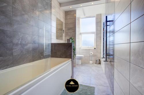 a bathroom with a tub and a toilet and a window at Stylish 1 bed Apt By Livra Estate Short Lets & Serviced Accommodation Sutton With Free Parking in Sutton