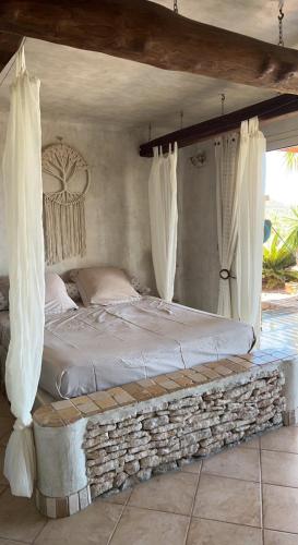 un lit dans une chambre avec un cadre de lit en pierre dans l'établissement Villa Ghjulia, à Porto-Vecchio