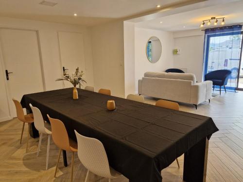 a dining room with a black table and chairs at Le Zénith - 3 chambres, 3 sdb, climatisé - 8 pers max - Réservation à la chambre possible - Local à vélos in Lagnieu