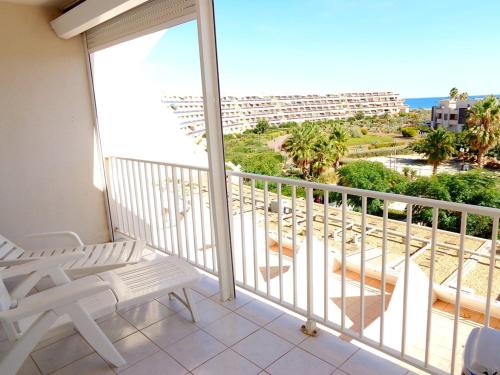 d'un balcon avec une chaise blanche et une vue sur l'océan. dans l'établissement Appartement Natura Beach 3 chambres NB303 - 8 personnes, au Cap d'Agde
