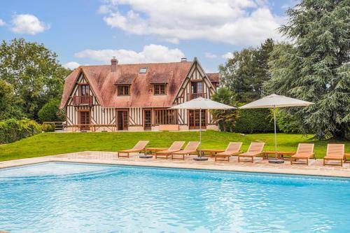 une maison avec une piscine avec chaises et parasols dans l'établissement Somptueuse Villa à 5 minutes de Deauville, 18 couchages, piscine, billard, salle de jeux, à Bonneville-sur-Touques
