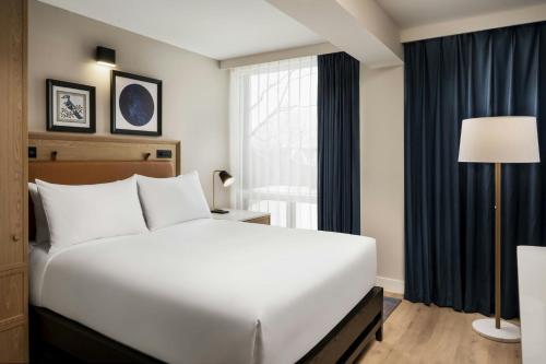 a bedroom with a large white bed and a window at Mont Gabriel, Sainte-Adèle, a Tribute Portfolio Resort in Sainte-Adèle