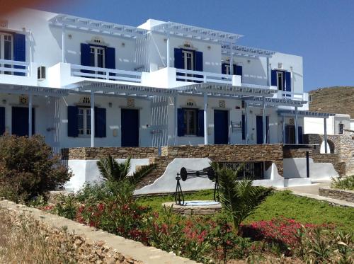 a large white building with blue windows and a camera at Nostos Beachfront Apartments & Studios in Agios Ioannis Tinos