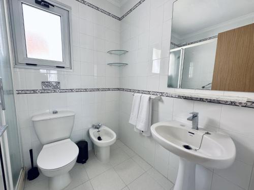 a white bathroom with a toilet and a sink at Apartamentos Turísticos Santo Rostro in Chipiona