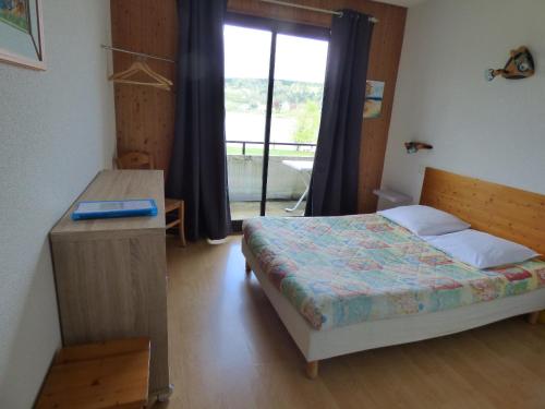 a bedroom with a bed and a table and a window at Hotel Restaurant La Chaumiere du Lac in Clairvaux-les-Lacs