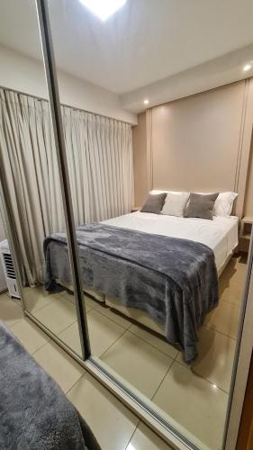 a bedroom with a large bed and a mirror at Vista Park Sul in Brasília