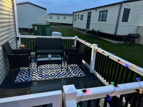 a balcony with chairs and a table on a deck at Holiday Park Caravan Fluffy in Harts Holiday Park in Leysdown-on-Sea