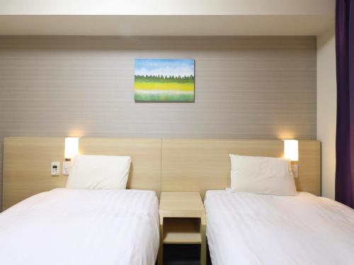 a bedroom with two beds and a painting on the wall at Dormy Inn Sapporo Annex in Sapporo