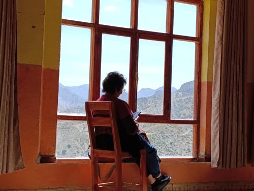 a woman sitting in a chair looking out of a window at KASBAH Atlas-Aberdouz in Aït Hattab