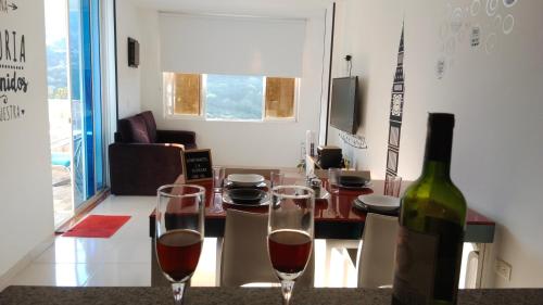 a bottle of wine sitting next to two wine glasses at Apartahotel La Terraza - San Gil in San Gil